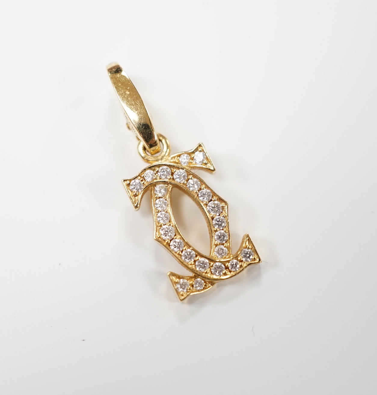 A modern Cartier 750 yellow metal and diamond chip set double C drop pendant, signed and numbered NE6304, overall 25mm, gross weight 2.6 grams, with Cartier box.